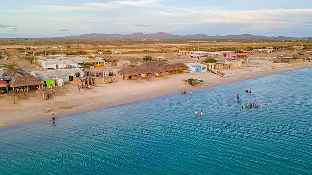Scenic view of Cabo de la Vela, La Guajira, showcasing a coastal village with traditional huts and people enjoying the beach.